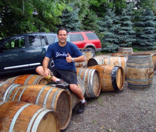 Rob, owner, sitting on a row on liquor barrels giving a thumbs up